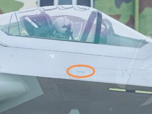 Alternative Text and a Caption for the J-20 image you provided are as follows:Alternative Text A high-angle close-up of a Chinese J-20 stealth fighter jet flying against a blue sky, showcasing its unique canard-delta wing design.