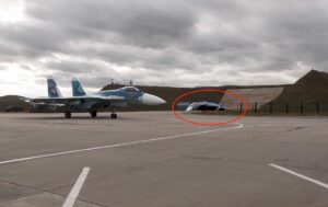 A deflated, crumpled inflatable decoy fighter jet lies on a military tarmac.