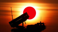 A ground-based missile launcher silhouetted against a rising sun, with a Japanese flag subtly integrated into the background, symbolizing the military deployment and strategic partnership between the two nations.
