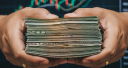 A close-up image of a person's hands holding a stack of neatly arranged paper currency notes, with a blurred background showing a graph or financial chart. The image conveys the concepts of government finance, investment, and financial security.