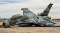 A deflated, crumpled inflatable decoy fighter jet lies on a military tarmac.