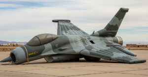 A deflated, crumpled inflatable decoy fighter jet lies on a military tarmac.